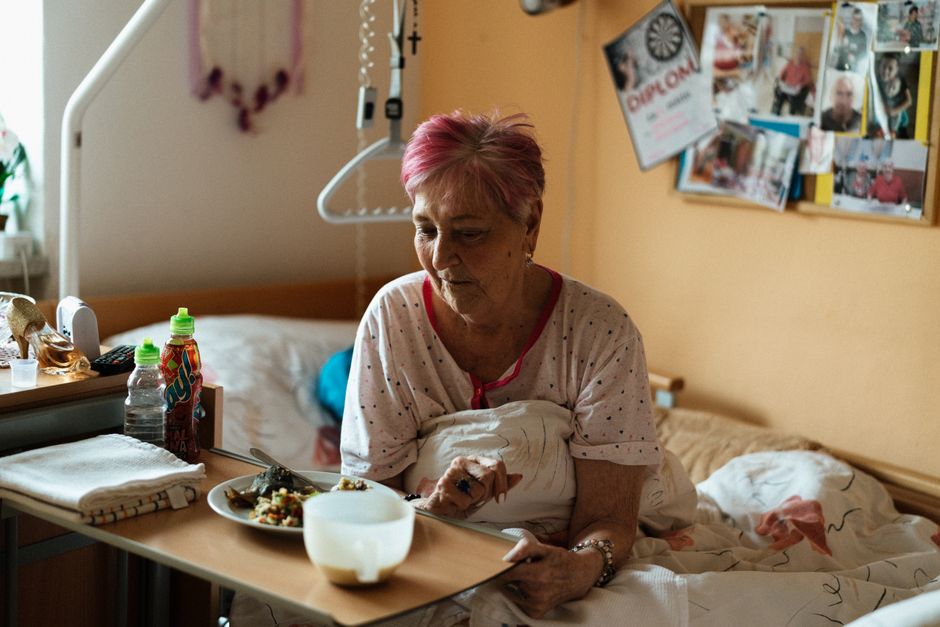 Elderly resident enjoying meal in care home dining area